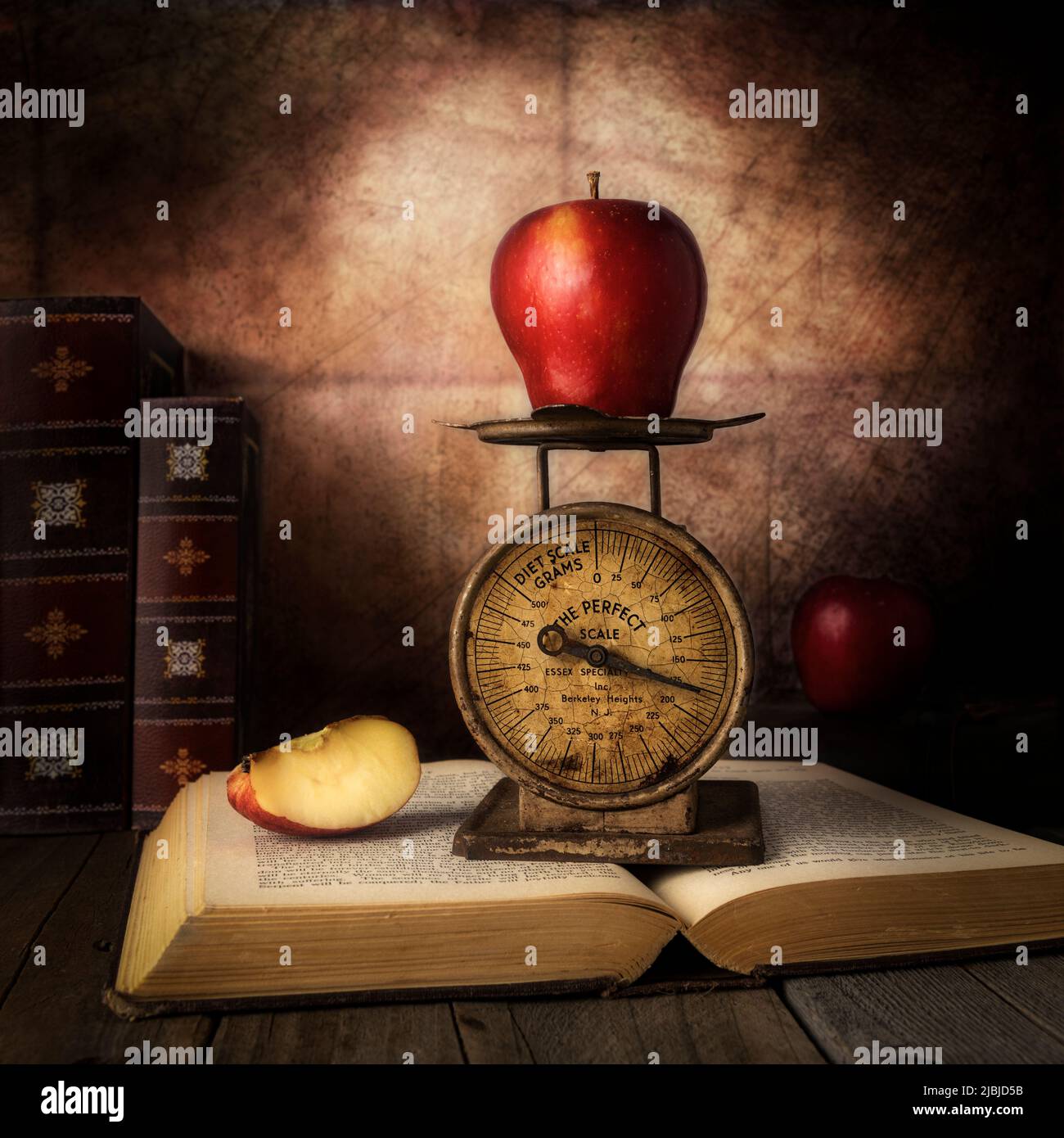 Roter Apfel mit vintage kleinen Maßstab auf der Spitze der antiken offenen Buch Stillleben Fotografie Stockfoto