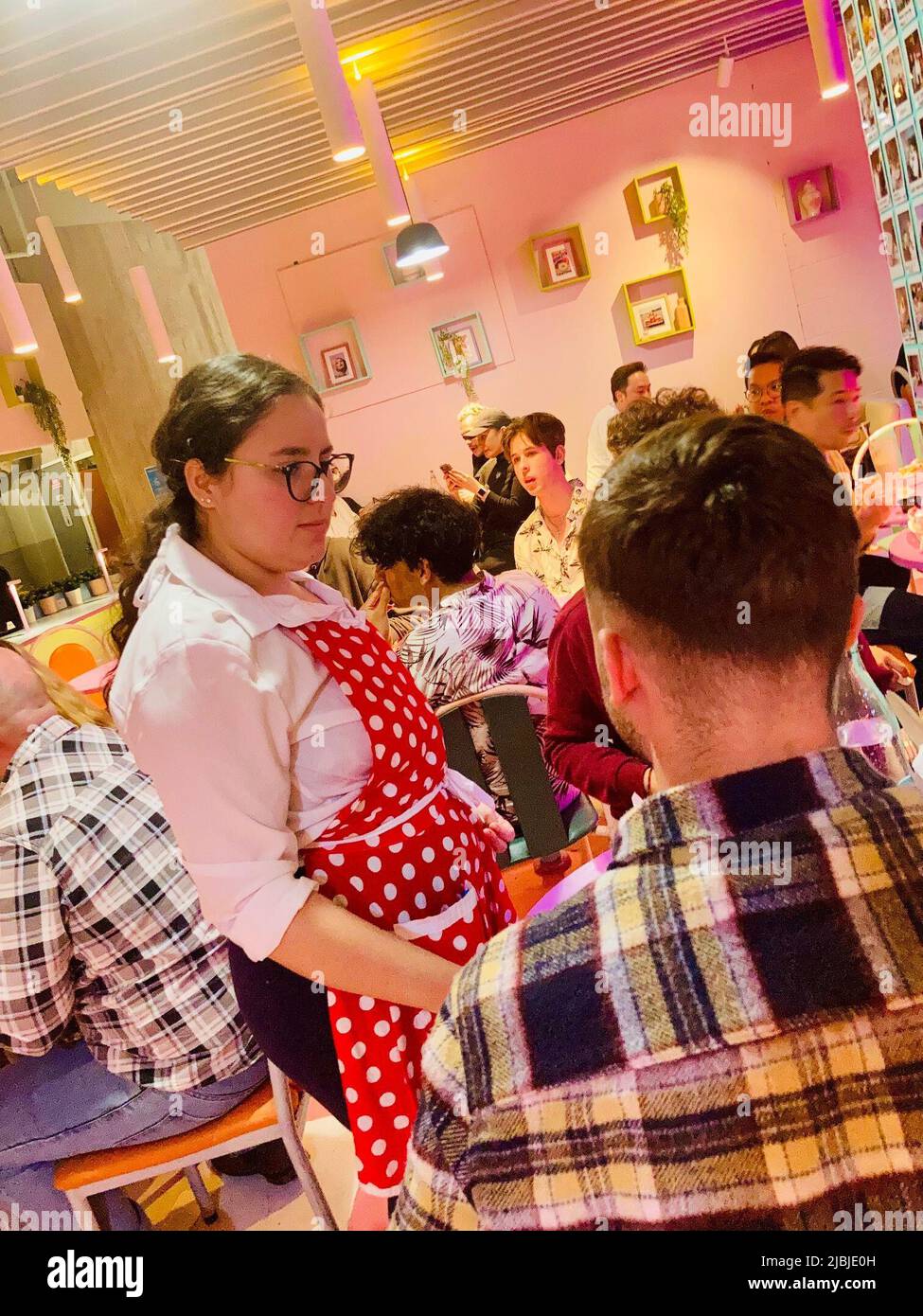Sydney, Australien. 25.. Mai 2022. Eine leicht verärgerte Kellnerin in rot-weißer Schürze serviert Burger und Pommes im Karen's Diner. Restaurants sind in der Regel stolz auf guten Service. Nicht so bei Karen's Diner in Australien, wo die Gäste mobbt und extra schlecht bedient werden. Das kuriose Konzept wird so gut angenommen, dass die Kette nun weltweit expandiert. (To dpa 'unhöfliche Kellner als Erfolgsrezept: Karen's Diner erobert Australien') Quelle: Carola Frentzen/dpa/Alamy Live News Stockfoto