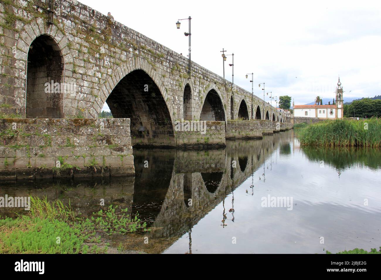 Mittelalterliche Steinbrücke über den Fluss Lima, Kirche Santo Antonio da Torre Velha aus dem 18.. Jahrhundert auf der gegenüberliegenden Flussseite, Ponte de Lima, Portugal Stockfoto