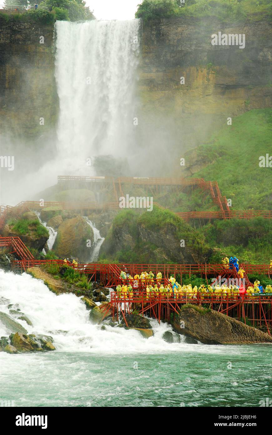 Eine Gruppe von Touristen, die gelbe Regenmäntel tragen, gehen die Promenade in Richtung Bridal Veil Falls auf der amerikanischen Seite der Niagarafälle Stockfoto