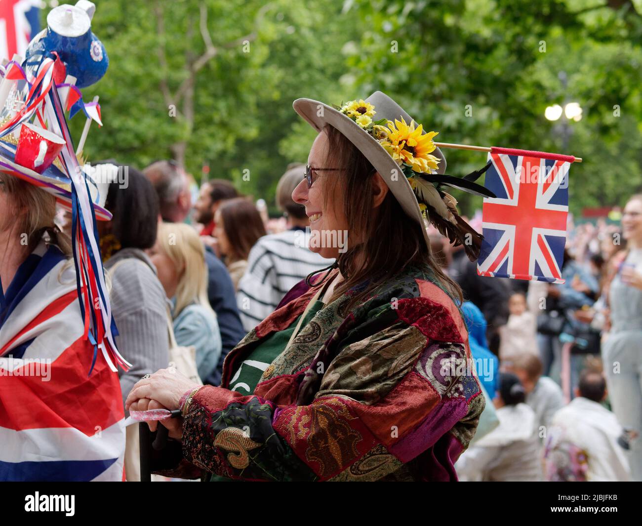 London, Greater London, England, 04 2022. Juni: Jubilee Concert at the Mall. Frau mit einem Hut, der mit gelben Blumen bedeckt ist, lächelt. Stockfoto