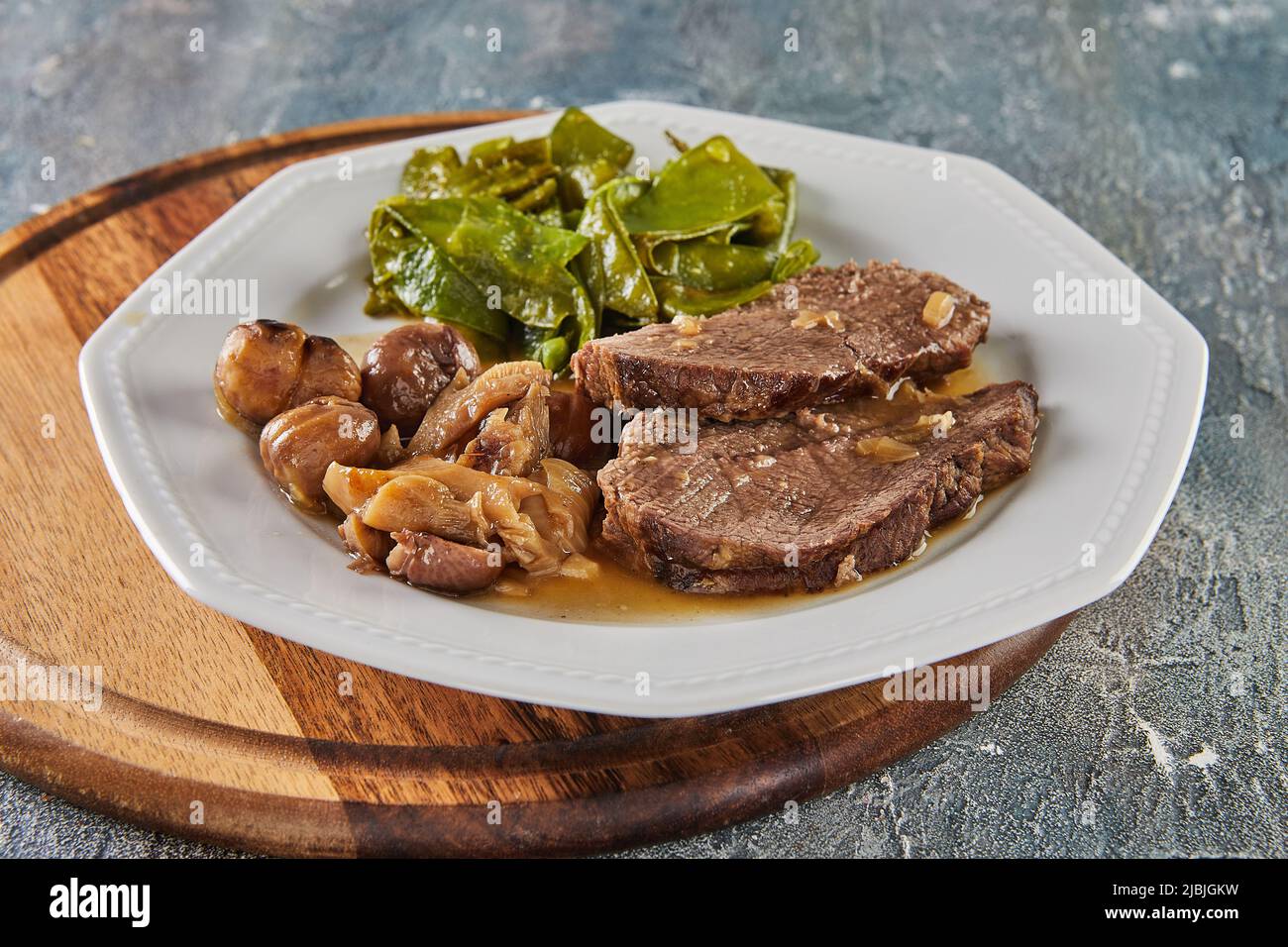 Roastbeef mit Kastanien und Waldpilzen und grünen Erbsen. Französisches Gourmetessen Stockfoto