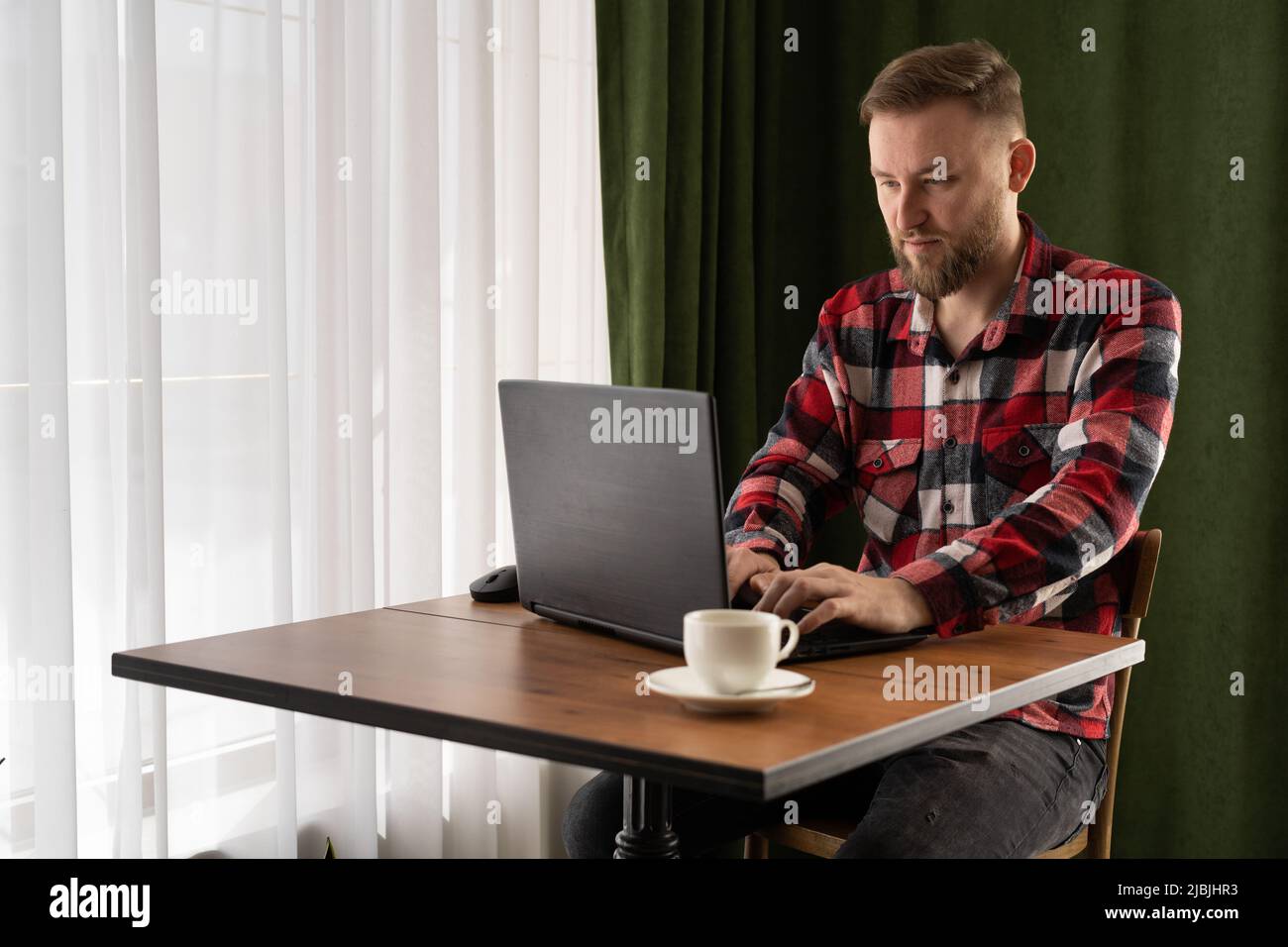Freiberufler-Konzept, kaukasischer Freiberufler, der im Café mit Laptop arbeitet, Telearbeit, Student, der auf dem Tastatur-pc tippt, sitzt im Café Stockfoto