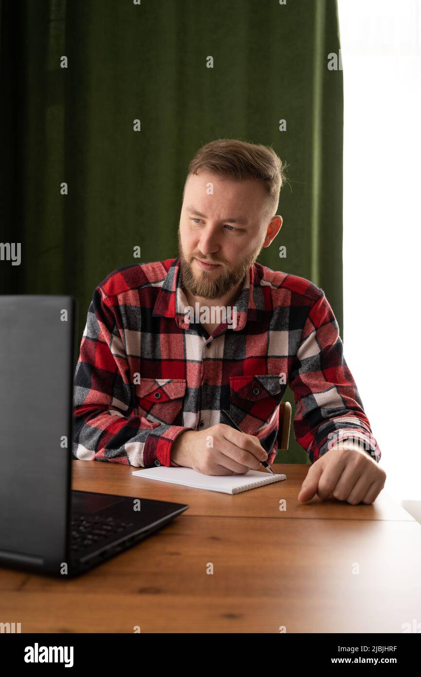 Erwachsene Studenten schreiben Informationen von einem Laptop auf, während sie sich auf einen Vortrag auf einem Universitätscampus vorbereiten, während ein Hipster auf einem PC arbeitet Stockfoto