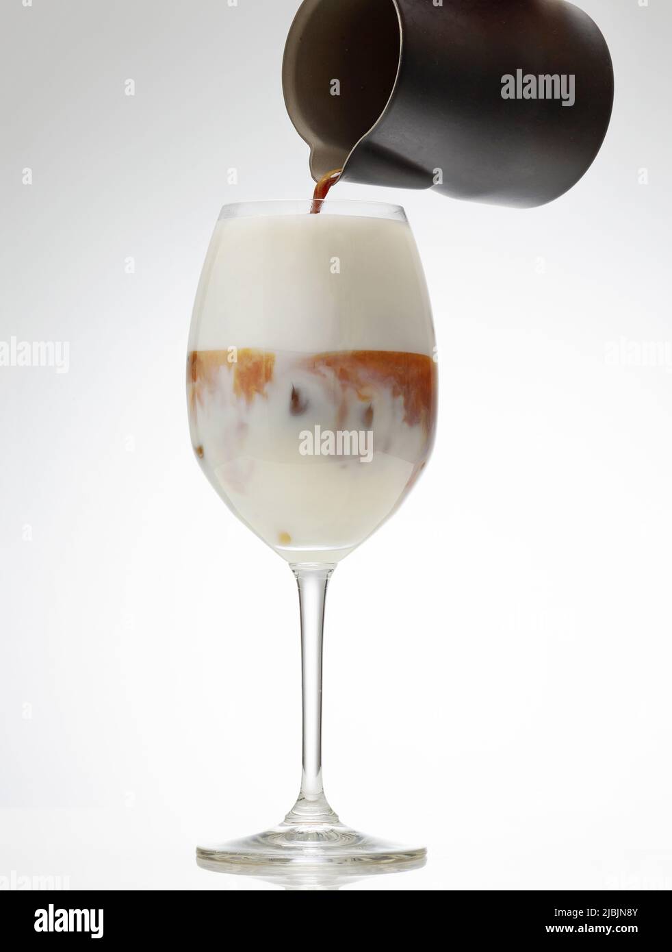 Kaffee-Espresso in ein Glas Eismilch für die Zubereitung von Cocktails gießen Stockfoto