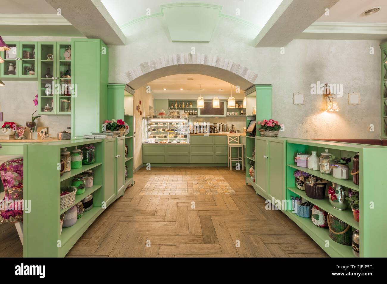 Gemütliches Café-Interieur mit pastellgrünen Möbeln, dekoriert mit Vintage-Kleinigkeiten Stockfoto