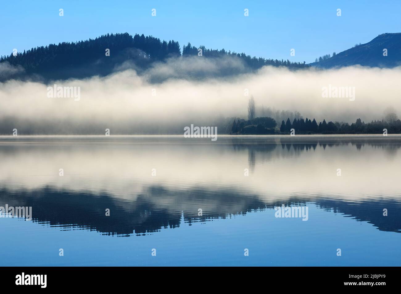 Morgennebel und bewaldete Hügel spiegeln sich in den ruhigen Gewässern des Lake Tutira, Neuseeland Stockfoto