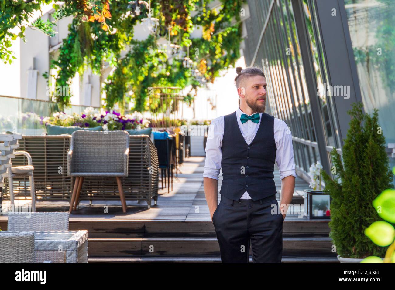 Junger Mann im Hipster-Look in einem Anzug mit Fliege in einem Sommer-Straßencafé Stockfoto
