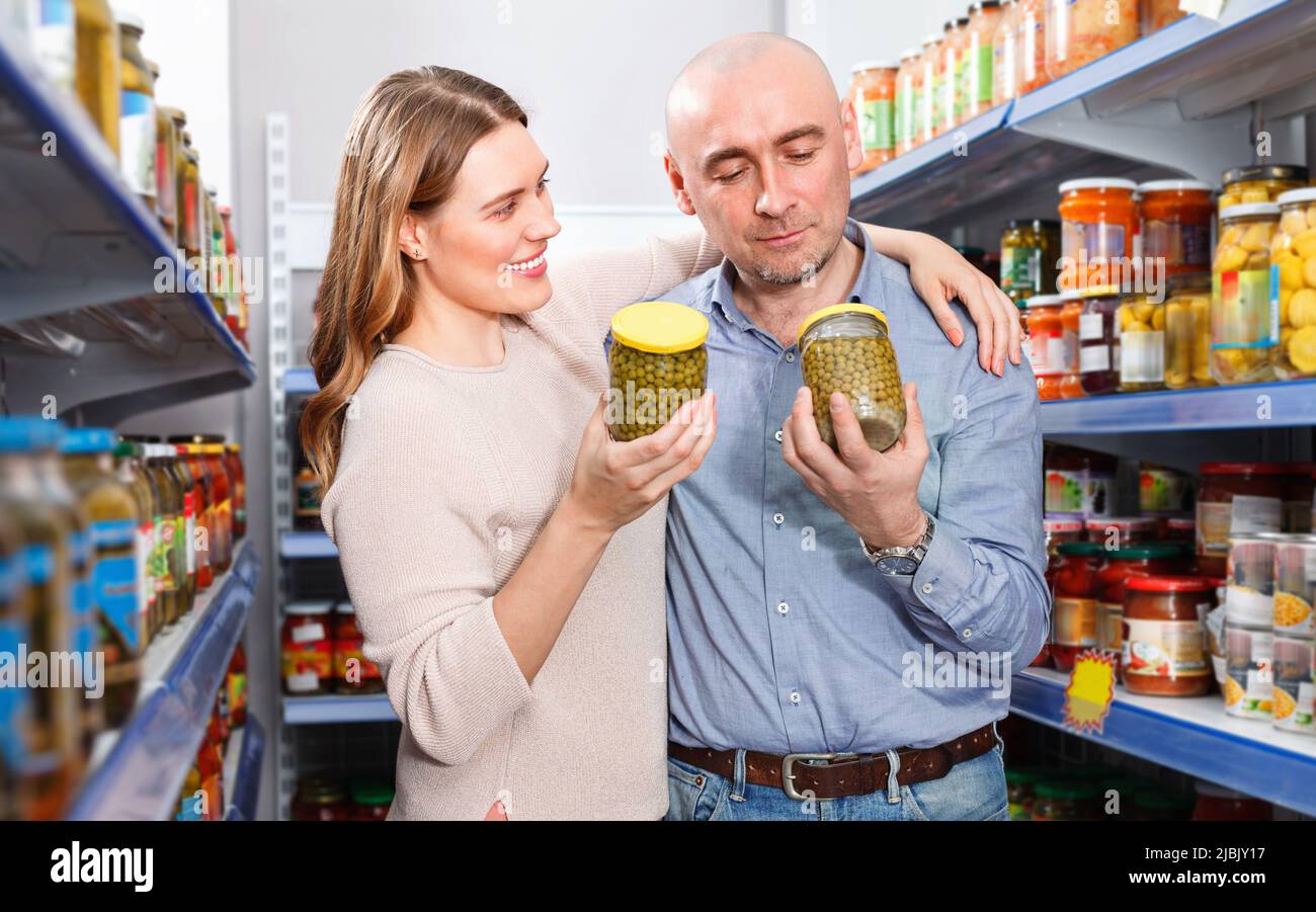 Positives Familienpaar, das Konserven im Lebensmittelgeschäft hält Stockfoto