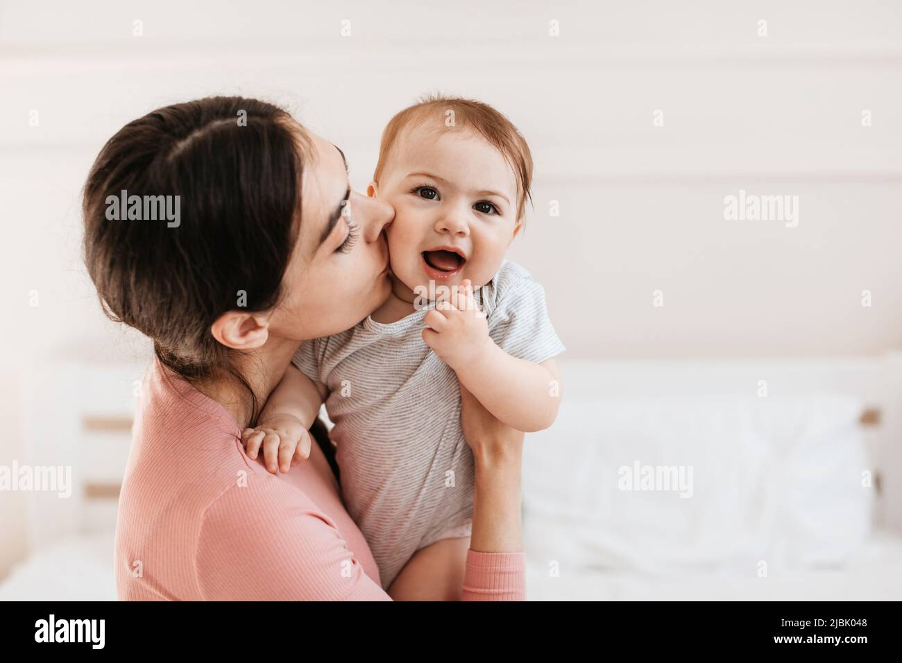 Nahaufnahme Porträt von liebevoller junger Mutter küssen kleine Kind in Wange, Bindung mit ihrem liebenswerten Sohn oder Tochter, freien Raum Stockfoto