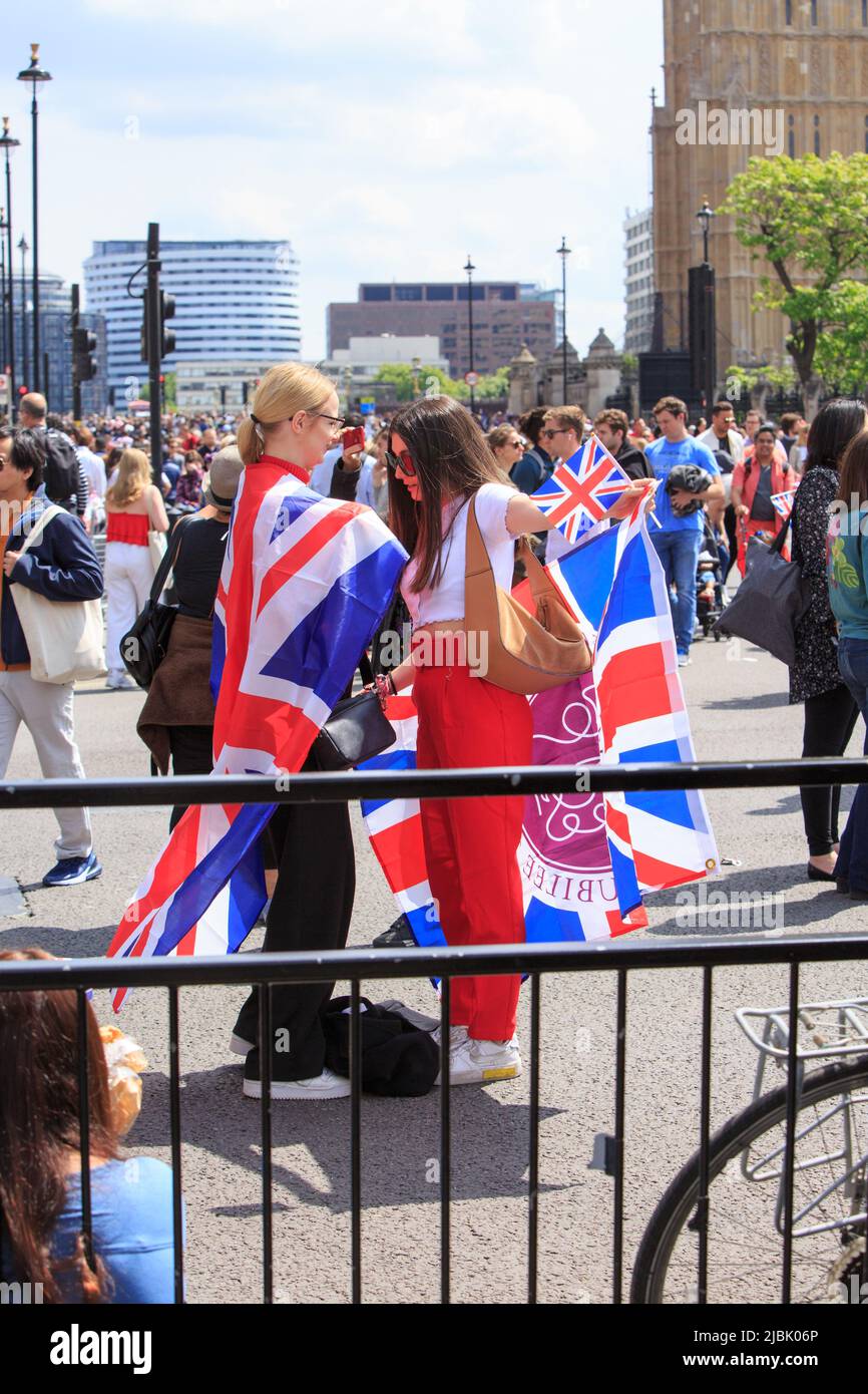 Westminster, London, 2022. Nachtschwärmer genießen das Feiertagswochenende in London, eingewickelt in Union Jack Flags. Stockfoto