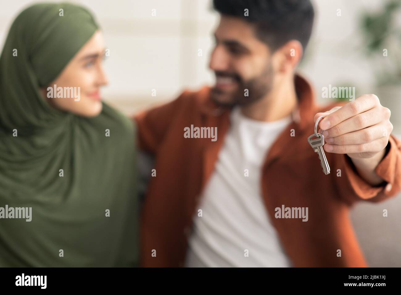 Glückliche Muslimische Ehegatten Zeigen Neuen Hausschlüssel Umarmt Sitzen Drinnen Stockfoto