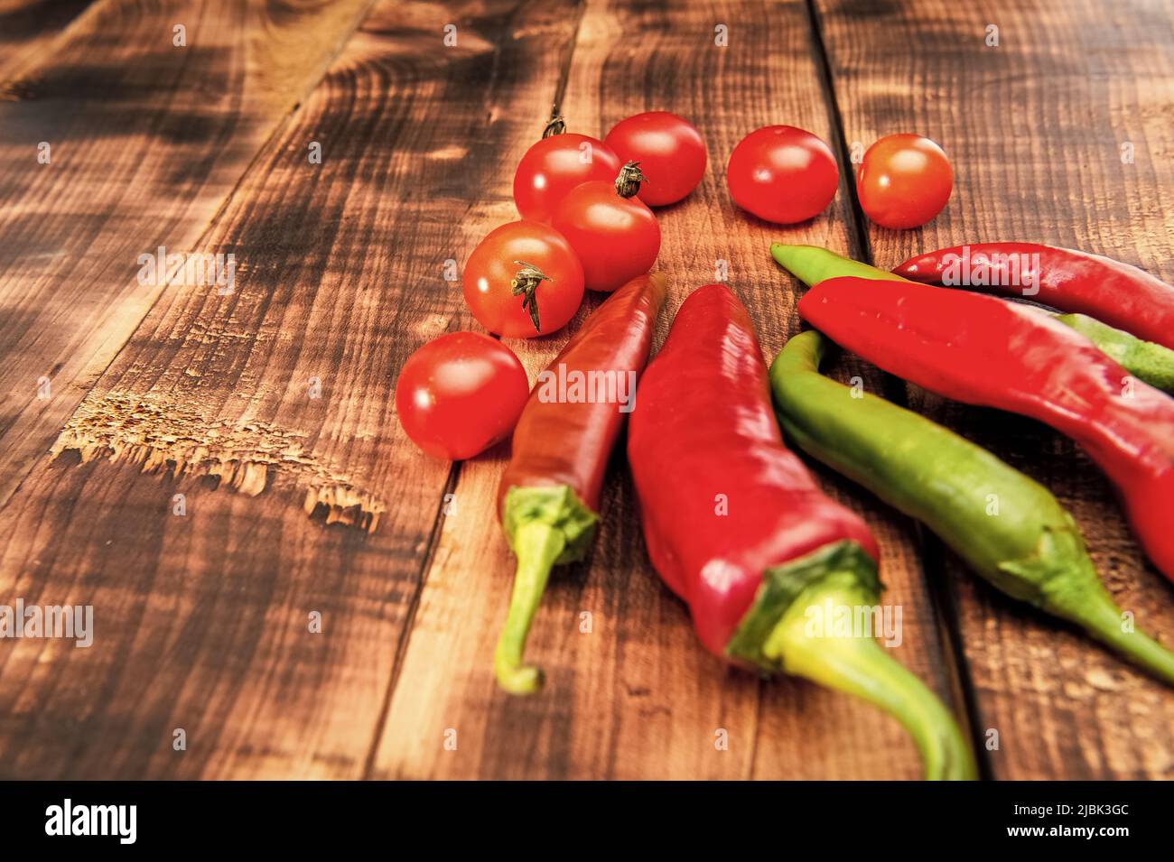 Rote und grüne Chilischoten Chilis und Kirschtomaten Gemüse Holzhintergrund, Essen Stockfoto