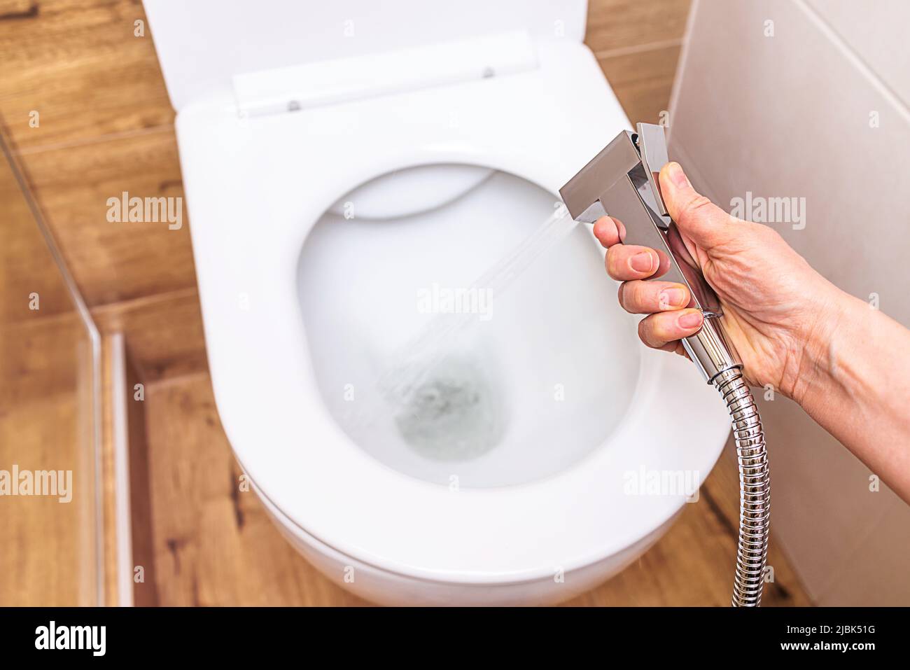 Nahaufnahme, in weiblicher Hand eine hygienische Dusche, vor dem Hintergrund einer modernen Toilette Stockfoto