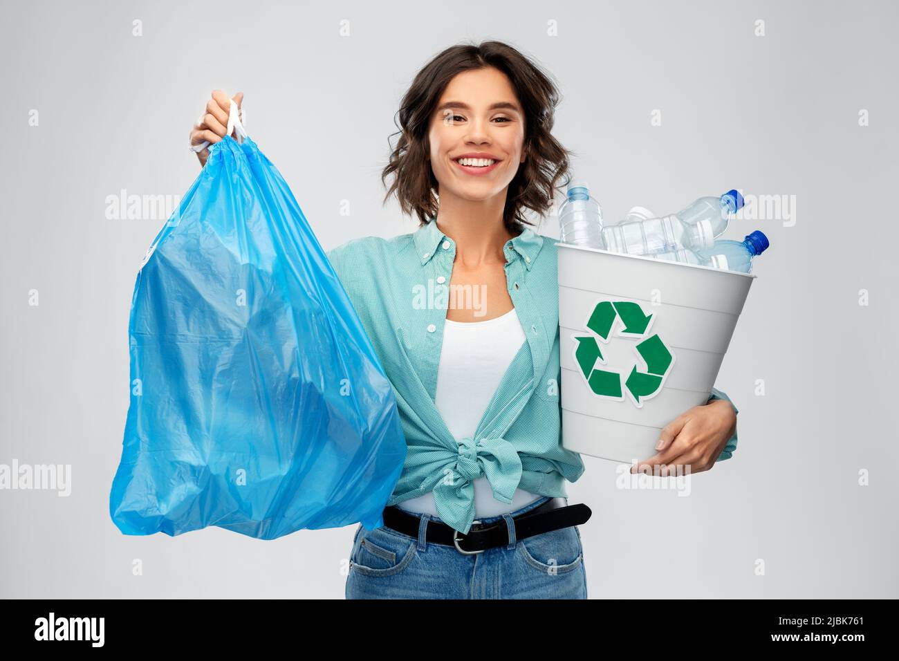Lächelnde Frau, die Plastikmüll und Müllbeutel sortiert Stockfoto