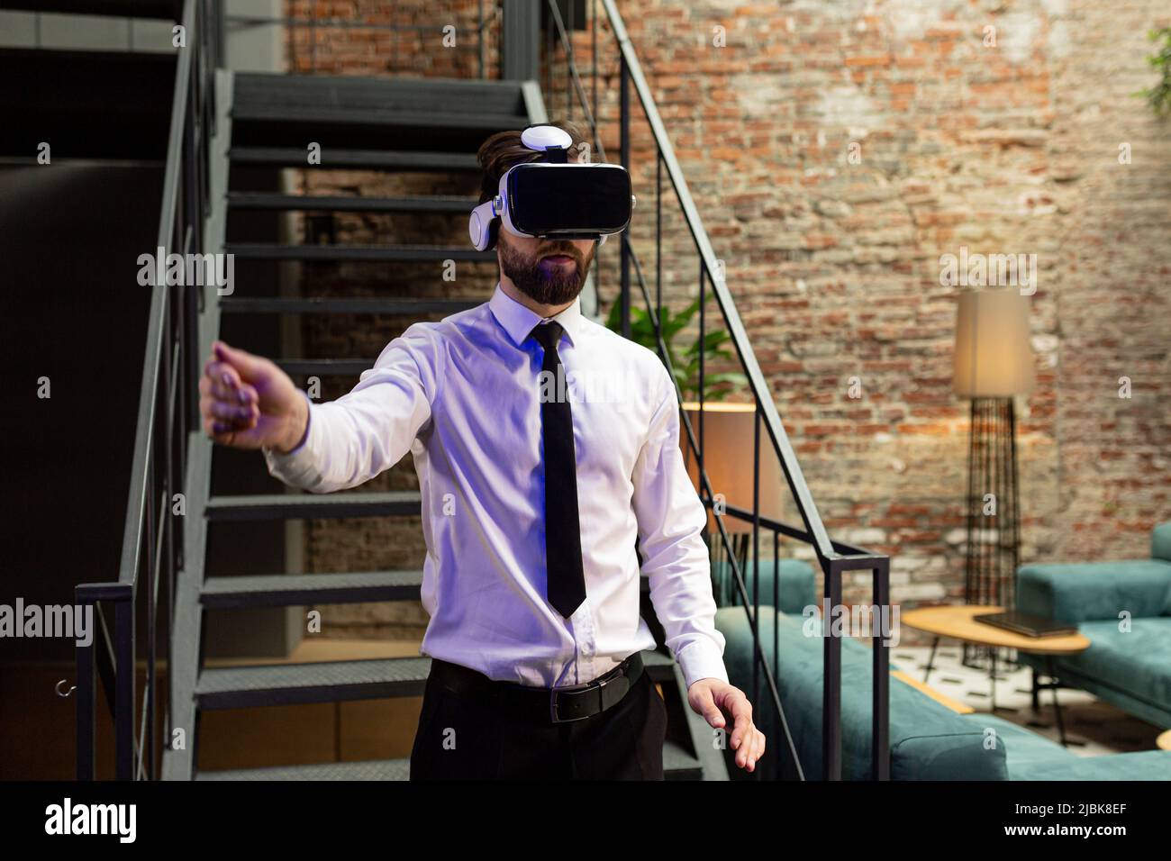 Ein Mann Büroleiter in formeller Kleidung trägt Virtual Reality vr Brille Swiping scrollende Online-Bilder in modernen Büro. Augmented Reality-Konzept Stockfoto