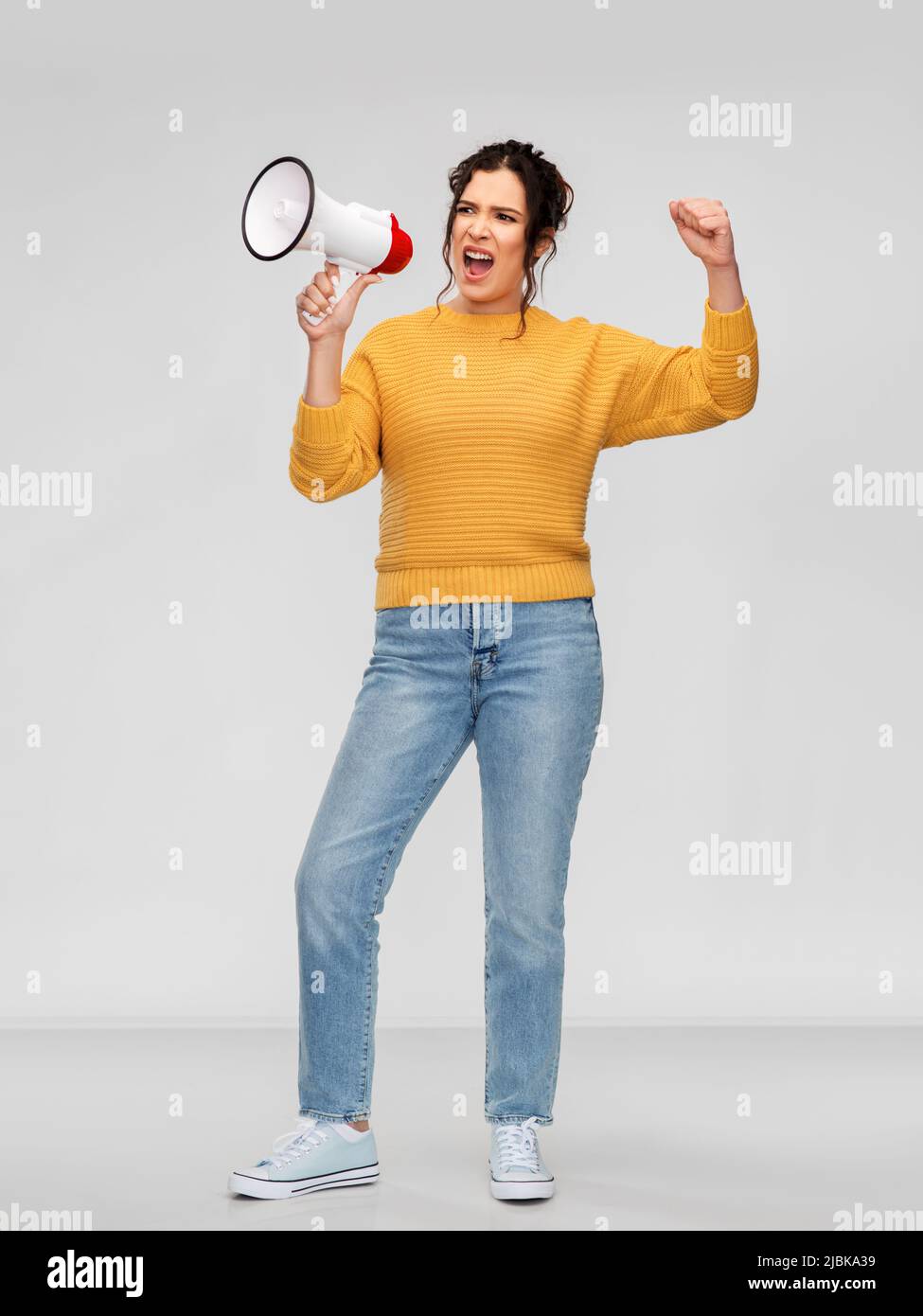 Wütende junge Frau, die mit dem Megaphon spricht Stockfoto