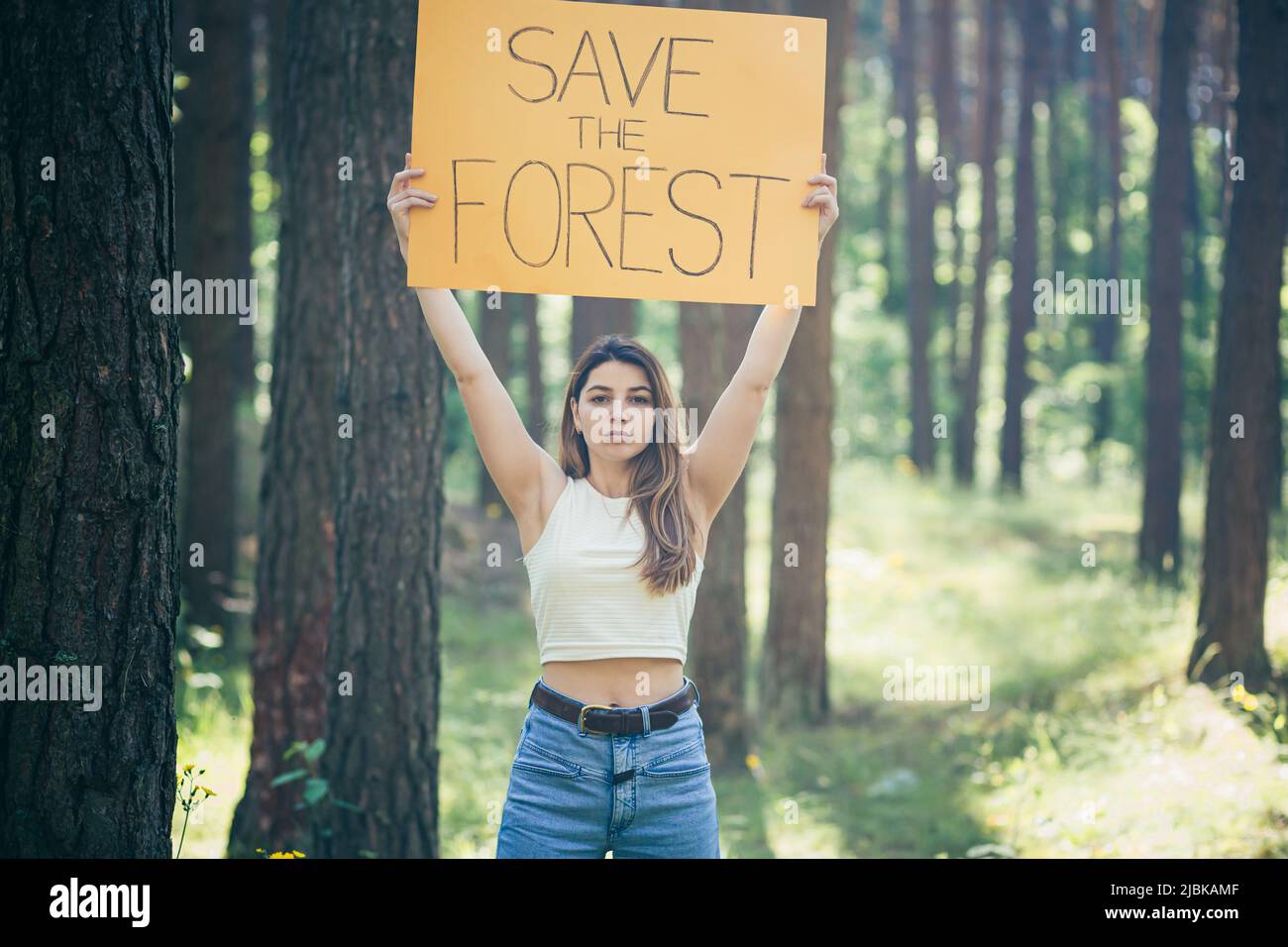 Junge schöne Frau ehrenamtliche Aktivistin im Wald mit einem Plakat speichern den Wald Stockfoto