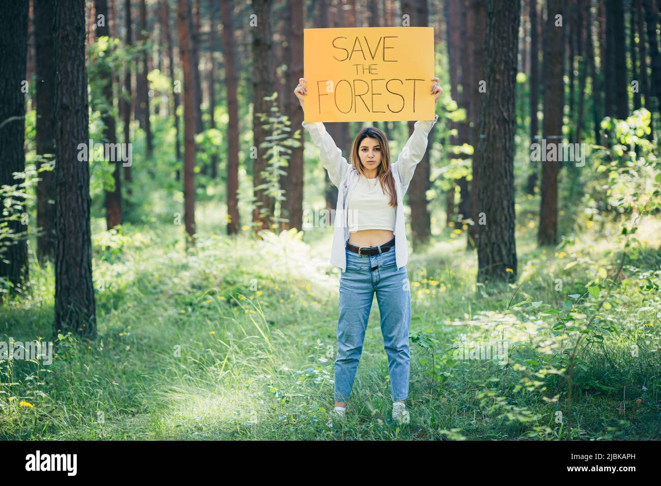 Junge schöne Frau ehrenamtliche Aktivistin im Wald mit einem Plakat speichern den Wald Stockfoto