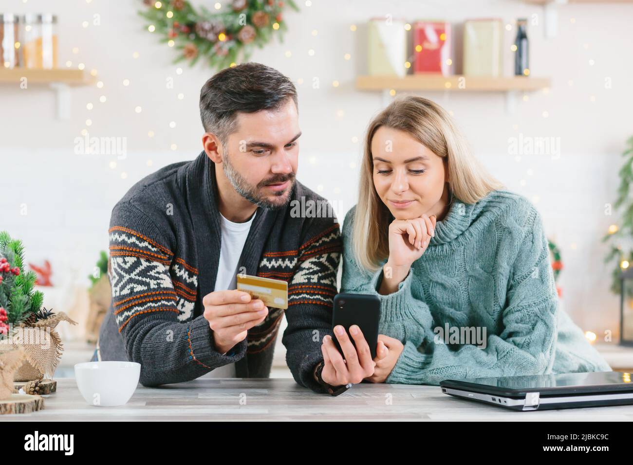 Junge glückliche Familie während des neuen Jahres und der Weihnachtsferien zu Hause freudig kaufen Geschenke online mit einem Smartphone und Kreditkarte Stockfoto