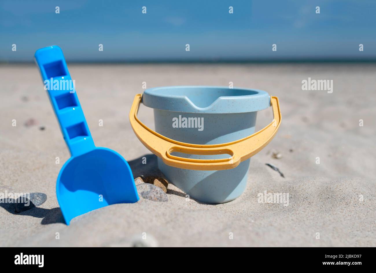 Nahaufnahme von Spielzeugeimer und Spaten am Sandstrand gegen Meer und blauen Himmel Stockfoto
