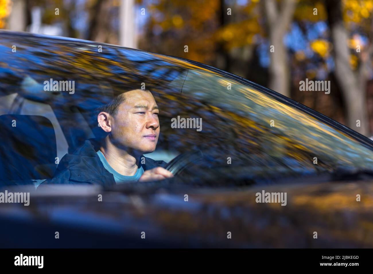 Ein nachdenklicher Asiat sitzt im Auto, der Fahrer wartet und ist traurig Stockfoto