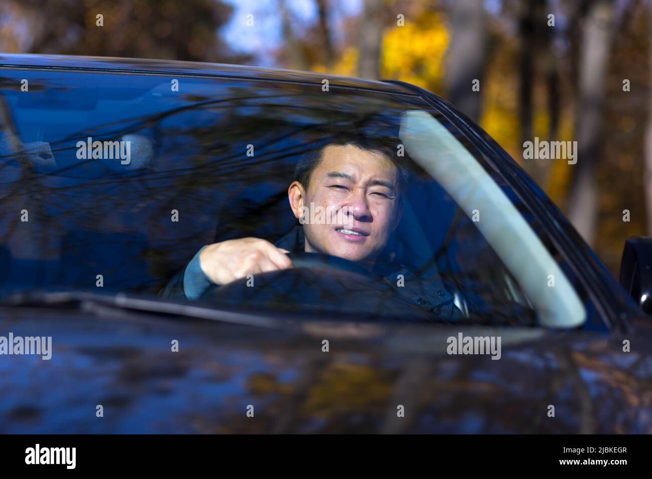 Ein nachdenklicher Asiat sitzt im Auto, der Fahrer wartet und ist traurig Stockfoto