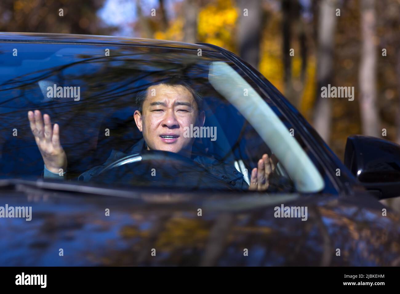 Wütender, wütender asiatischer Mann, der in einem Stau steht, piept und eilt. Sitzen im Auto. Verartert junge Geschäft männlich müde Fahrer im Auto. Str Stockfoto