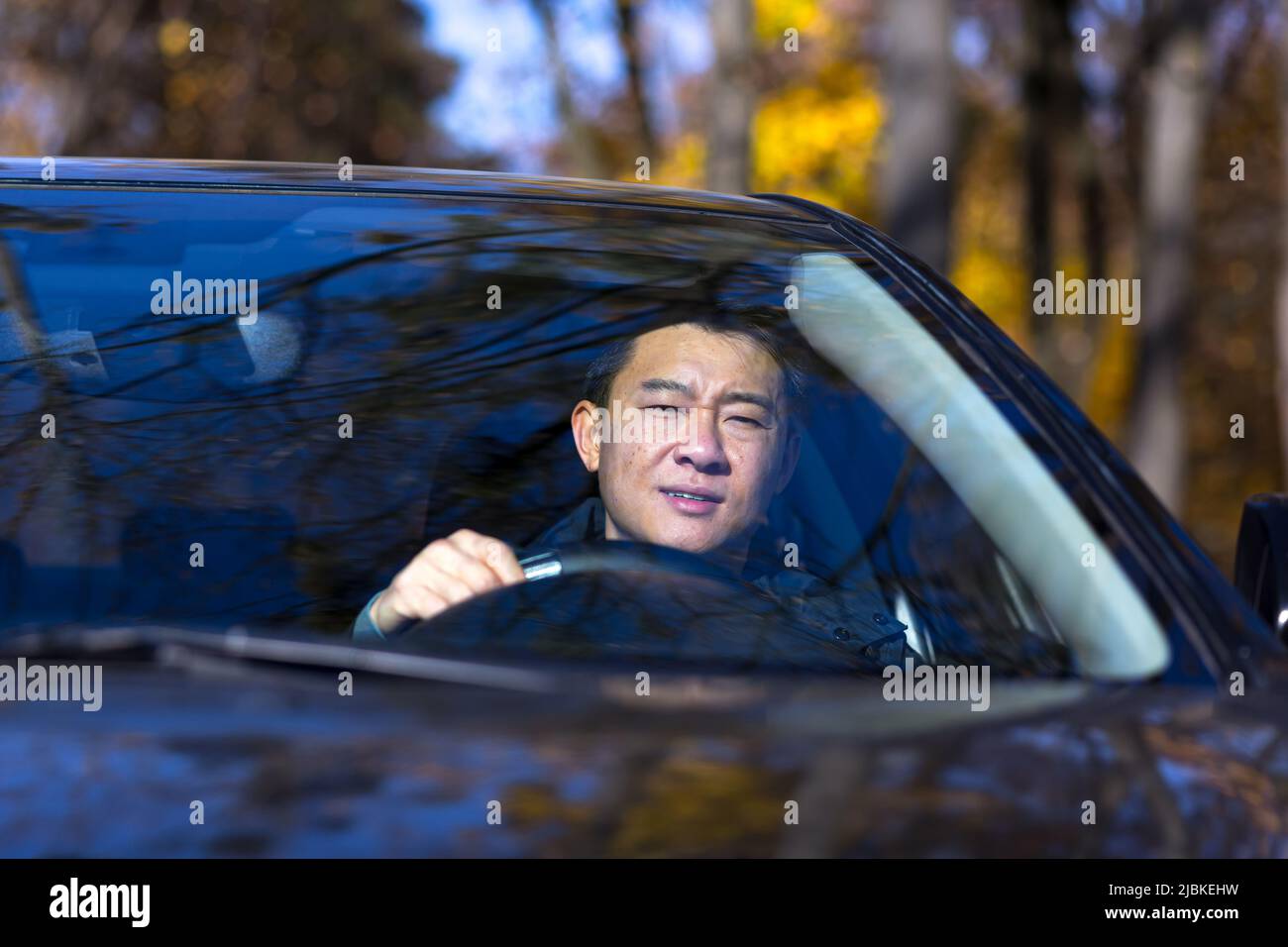 Ein nachdenklicher Asiat sitzt im Auto, der Fahrer wartet und ist traurig Stockfoto
