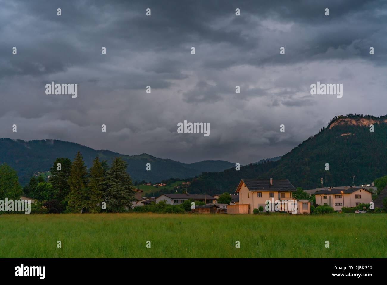 Dämmerung nach dem Sonnenuntergang in Dornbirn, Vorarlberg, Österreich. Tolle Stimmung mit interessanteren graublau Wolken, grünen Wiesen und Haus Stockfoto