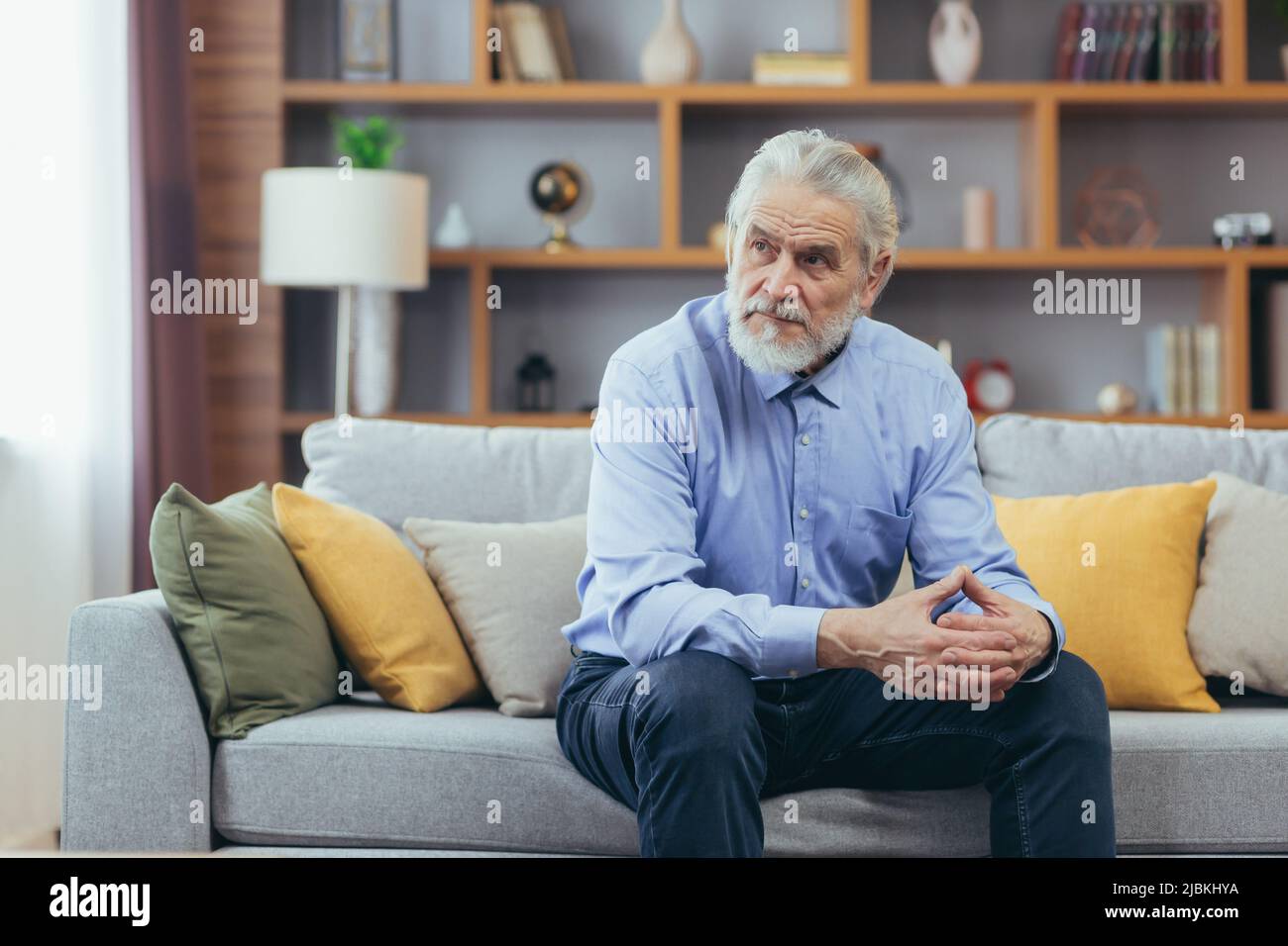 Ernst für nachdenklichen Großvater Mann sitzt auf dem Sofa zu Hause Stockfoto