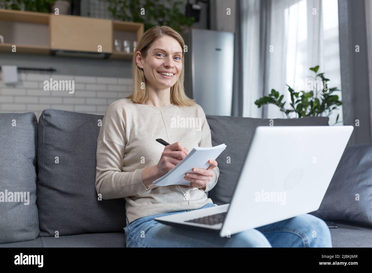Porträt einer Frau zu Hause, Schüler, die Unterricht aufzeichnen, mit Laptop für Online-Training, sitzen auf dem Sofa Stockfoto