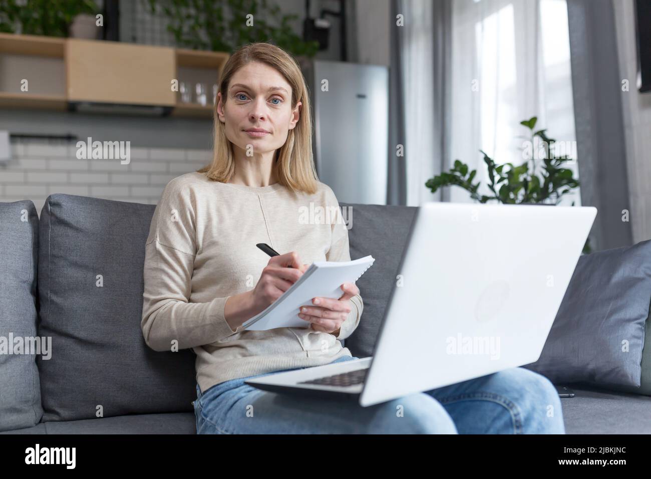 Porträt einer Frau zu Hause, Schüler, die Unterricht aufzeichnen, mit Laptop für Online-Training, sitzen auf dem Sofa Stockfoto