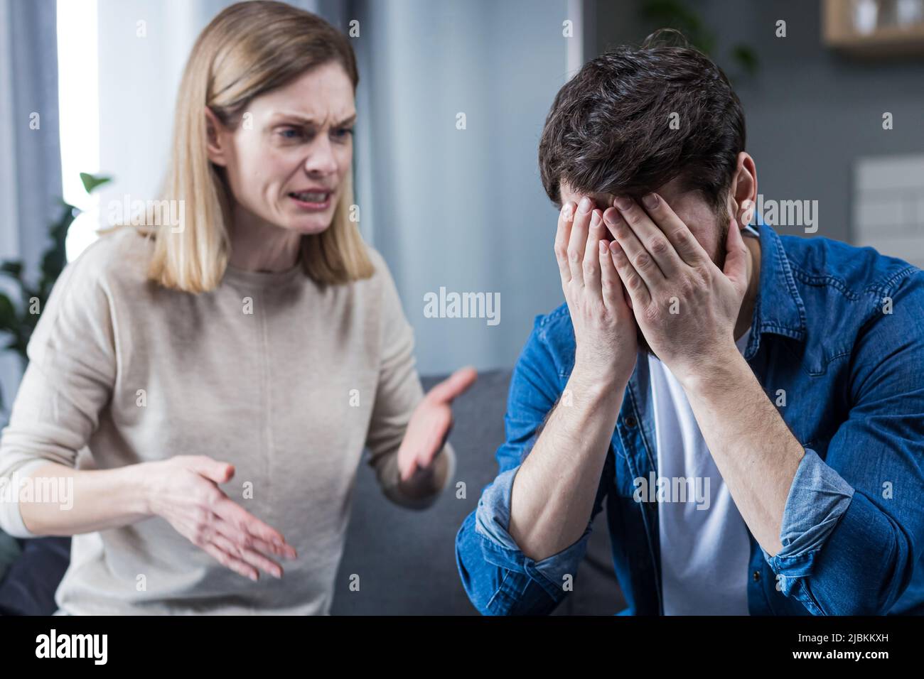 Familienkonflikt, Streit, Missverständnis. Die Frau schreit verzweifelt nach ihrem Mann und weint. Der Mann hört zu und bedeckt sein f Stockfoto
