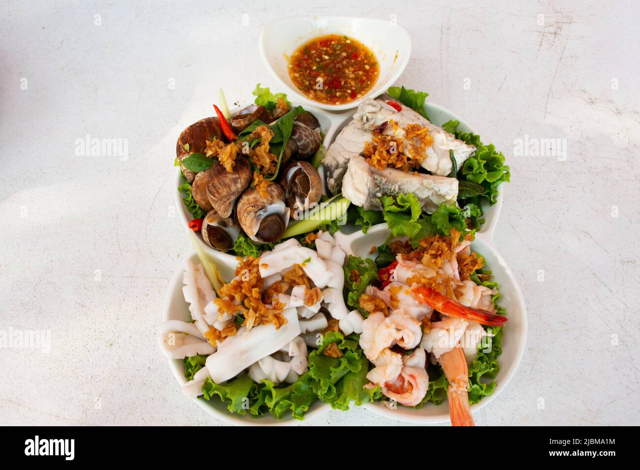 Verschiedene Meeresfrüchte weich gekocht auf Gemüse und moderne Keramikplatte mit würziger saurer Sauce für thailänder Gast Gast essen Getränk auf dem Tisch bei RE serviert Stockfoto