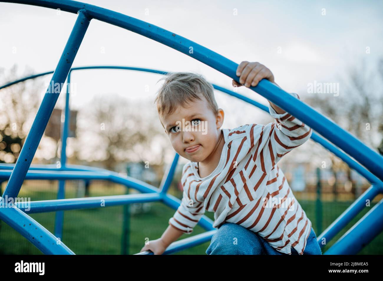 Ein kleiner Junge spielt auf dem Spielplatz im Freien. Stockfoto