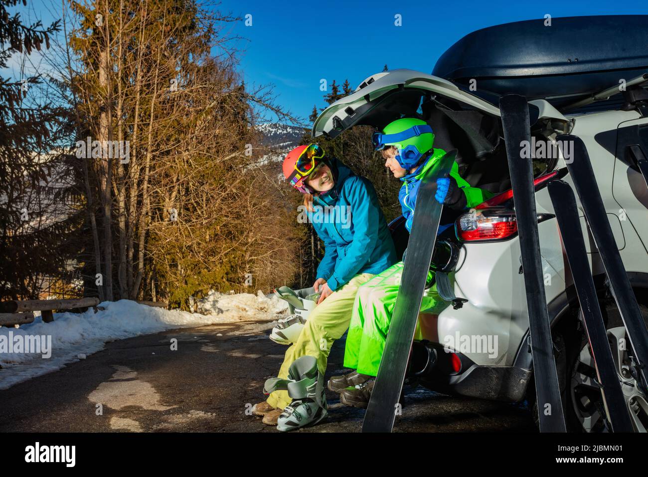 Mutter mit Sohn zog Stiefel an, um Ski und Snowboard zu fahren Stockfoto