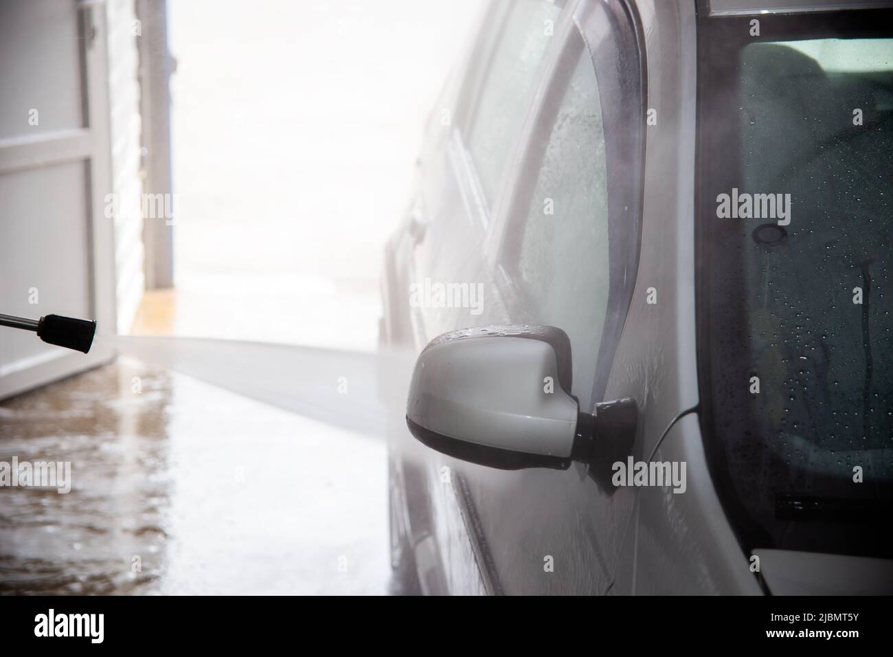 Ein Prozess der Spülung Seife sud auf silbernen Auto-Spiegel mit Druckwasserstrom an Self-Service-Indoor-Auto Waschstation Stockfoto