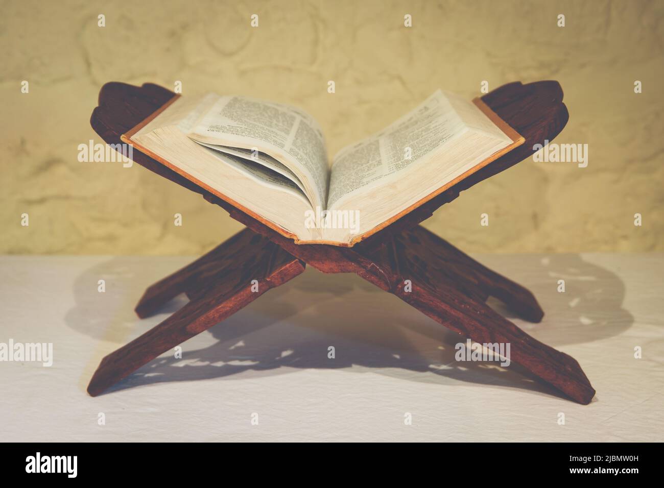 Öffnen Sie die Heilige Bibel auf einem kunstvollen Holzbuchständer in asketischer Umgebung für Meditation und Kontemplation Stockfoto