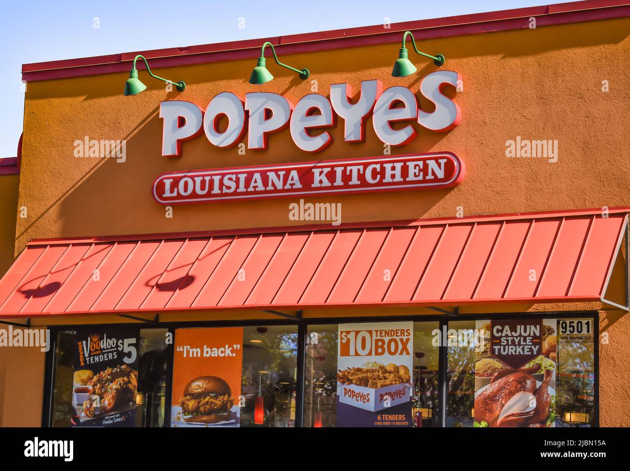 Popeyes Louisiana Kitchen, Außenmarke und Logo in weißen dreidimensionalen Buchstaben über orangefarbener Markise in einem orangefarbenen Strukturgebäude. Stockfoto
