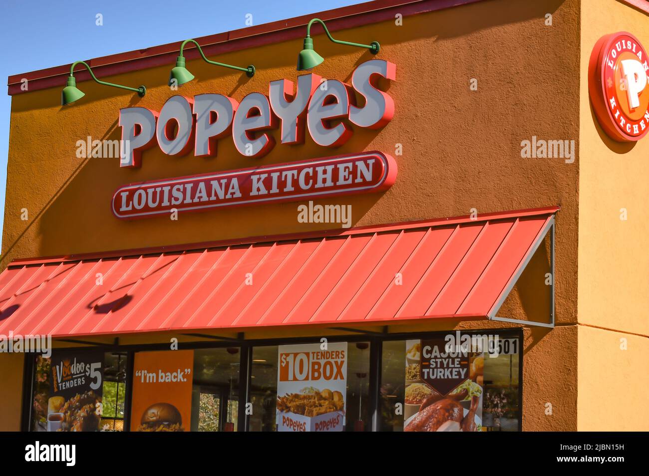 Popeyes Louisiana Kitchen, Außenmarke und Logo in weißen dreidimensionalen Buchstaben über orangefarbener Markise in einem orangefarbenen Strukturgebäude. Stockfoto