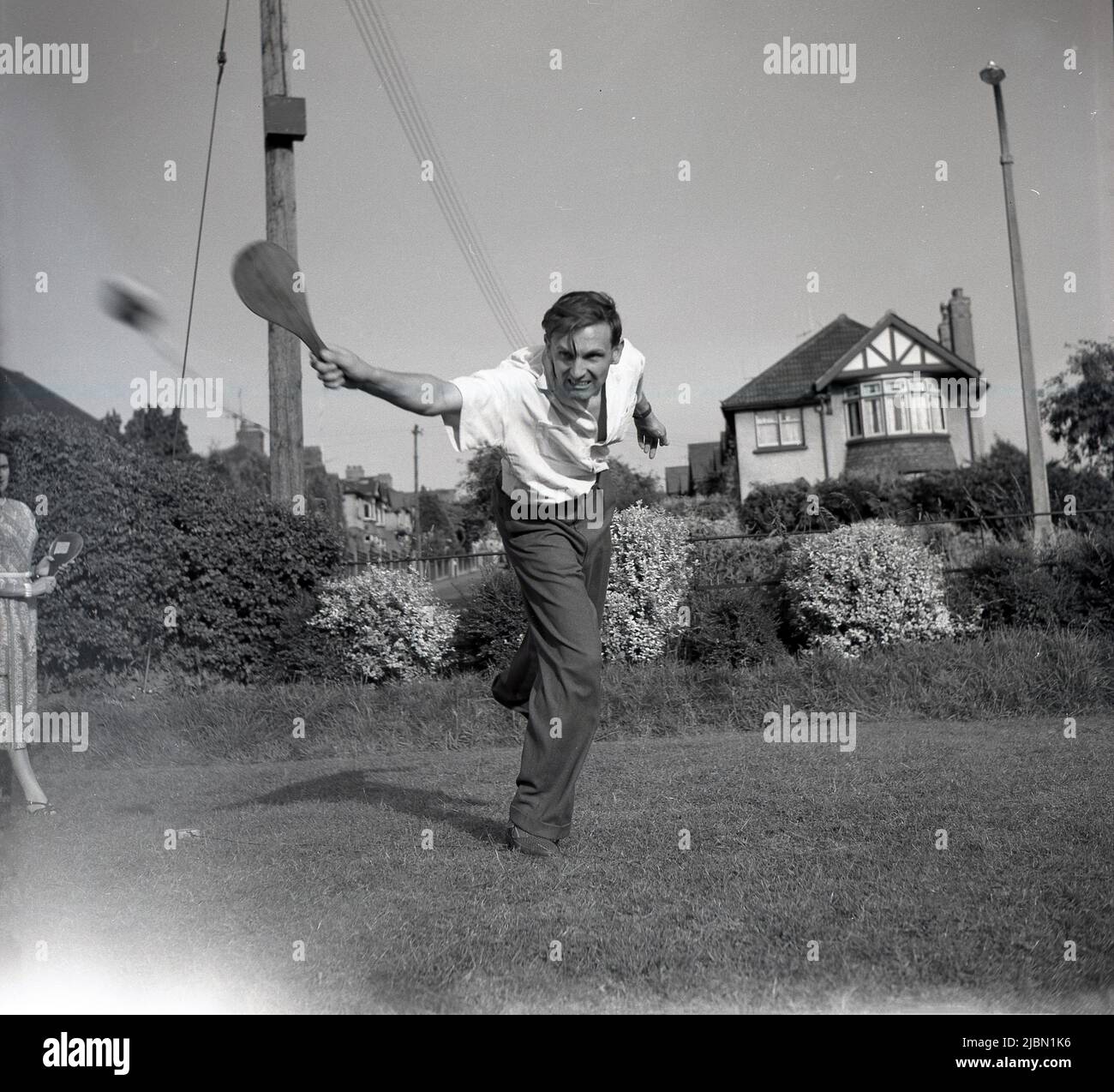1950s. Historisch, ein Mann mit einer Holzschläger oder Paddel auf einem Rasen in einem Garten, spielt ein Swing-Ball-Spiel, England, Großbritannien. Stockfoto