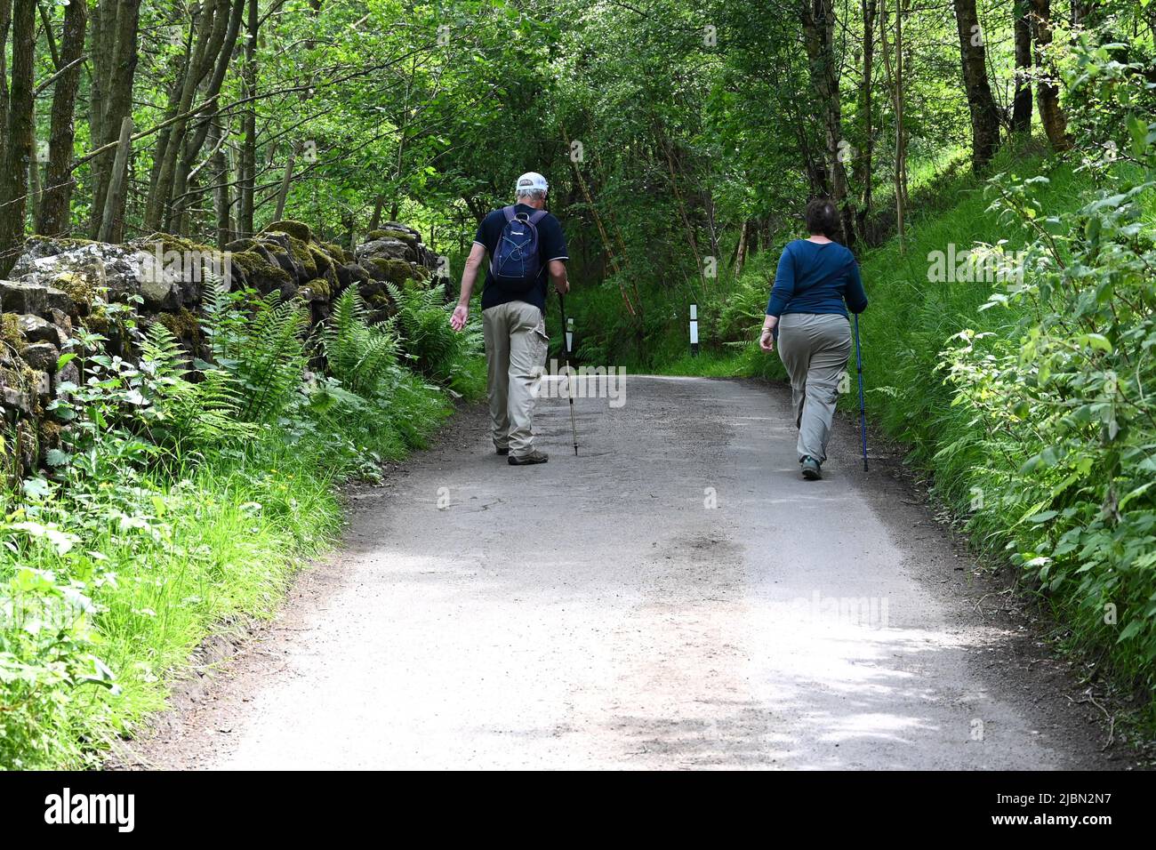 Ein Mann und eine Frau gehen an einer ruhigen Straße in Hayfield, Derbyshire Stockfoto