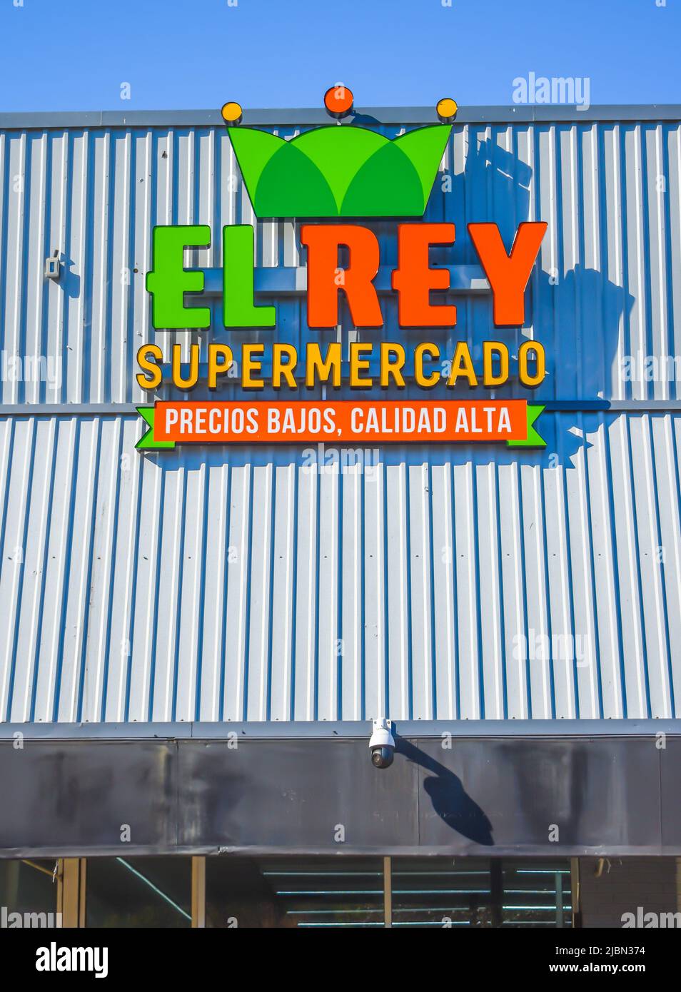 El Rey Supermarkt Außenfassade Marke und Logo Signage in grün und orange auf einem weißen, gerippten Metalldach mit einem klaren blauen leuchtenden Himmel. Stockfoto