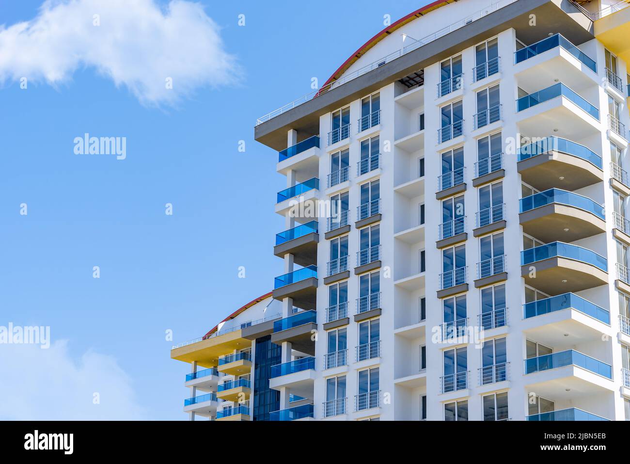 Gelbe und blaue moderne, belüftete Fassade mit Fenstern. Fragment eines neuen Wohn- oder Geschäftsgebäudes. Teil der Stadt Immobilien. Stockfoto