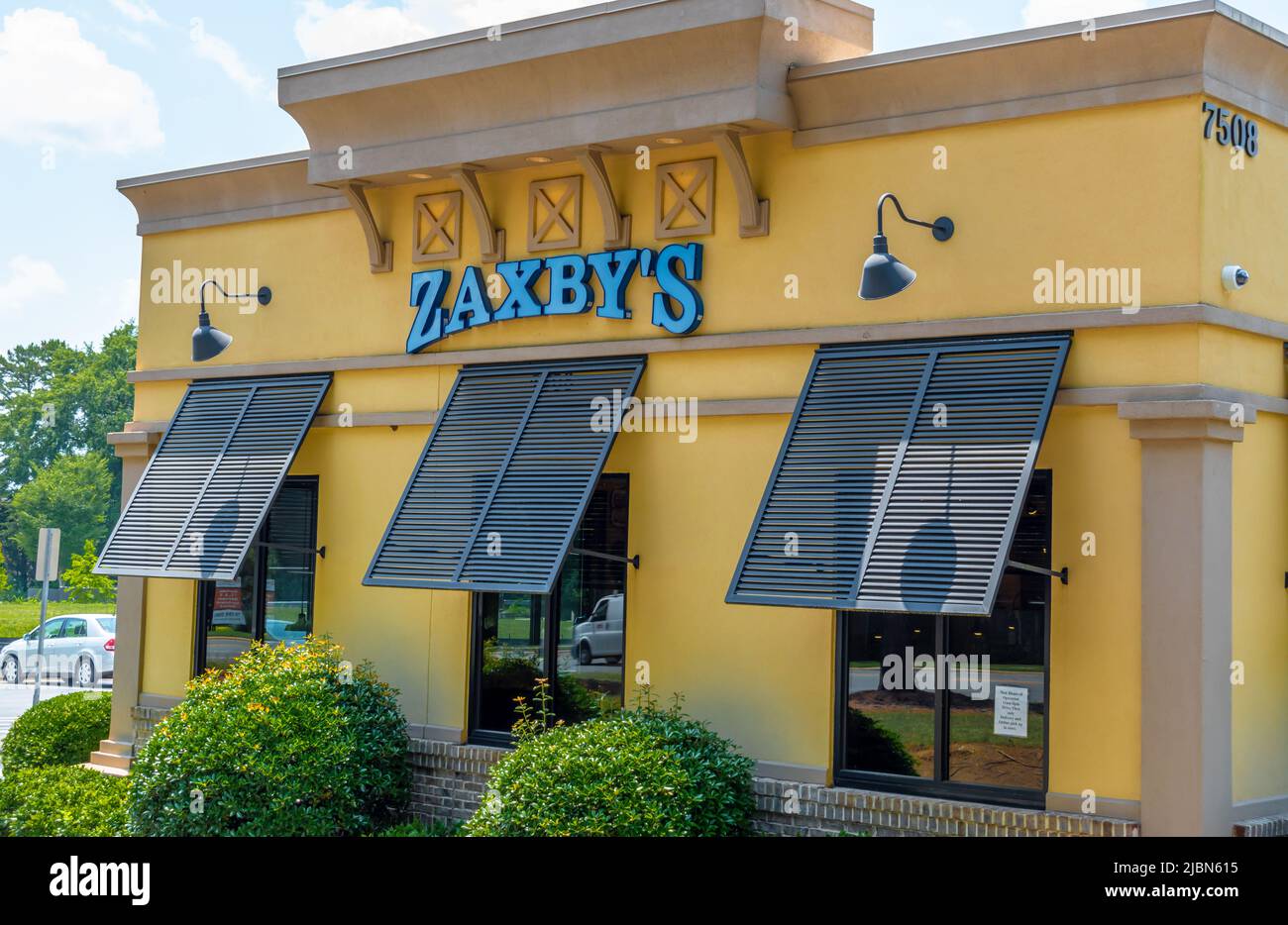 Zaxby's Restaurant Außenfassade Marke und Logo Beschilderung in pulverblauen Buchstaben auf einem gelb beigen Gebäude mit Fensterblenden an einem hellen sonnigen Tag. Stockfoto