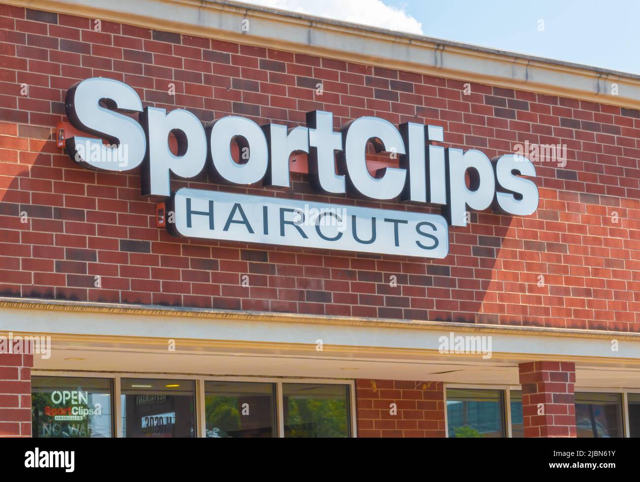 Sport Clips Frisuren Salon Außenfassade Marke und Logo Signage auf einem roten Backsteingebäude in weißen Buchstaben an einem hellen sonnigen Tag mit Schatten. Stockfoto