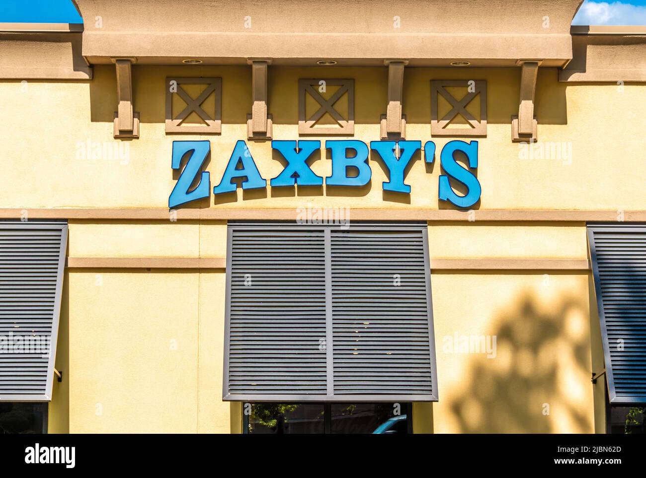 Zaxby's Restaurant Außenfassade Marke und Logo Beschilderung in pulverblauen Buchstaben auf einem gelb beigen Gebäude mit Fensterblenden an einem hellen sonnigen Tag. Stockfoto