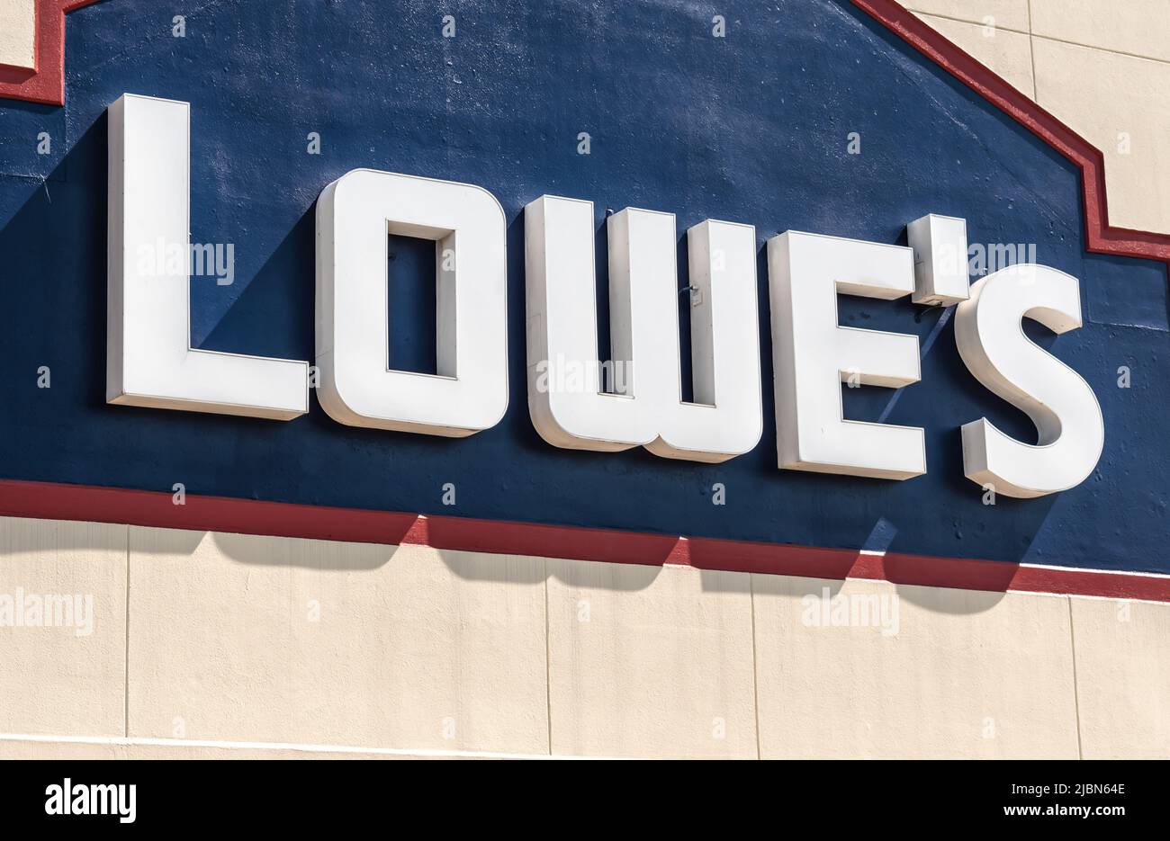 Die Fassadenmarke und das Logo von Lowe's Home Improvement Store in dreidimensionalen, weißen Buchstaben auf dunkelblauem Hintergrund bei sonnigem Tageslicht. Stockfoto