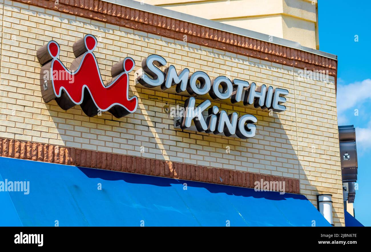 Smoothie King's Außenfassade-Marke und Logo-Beschilderung in weißen dreidimensionalen Buchstaben auf beigefarbenen Ziegelsteinen über strahlend blauer Markise bei Sonnenschein. Stockfoto